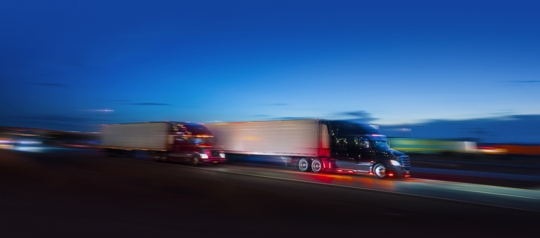 Semi-trucks driving on the highway at dusk